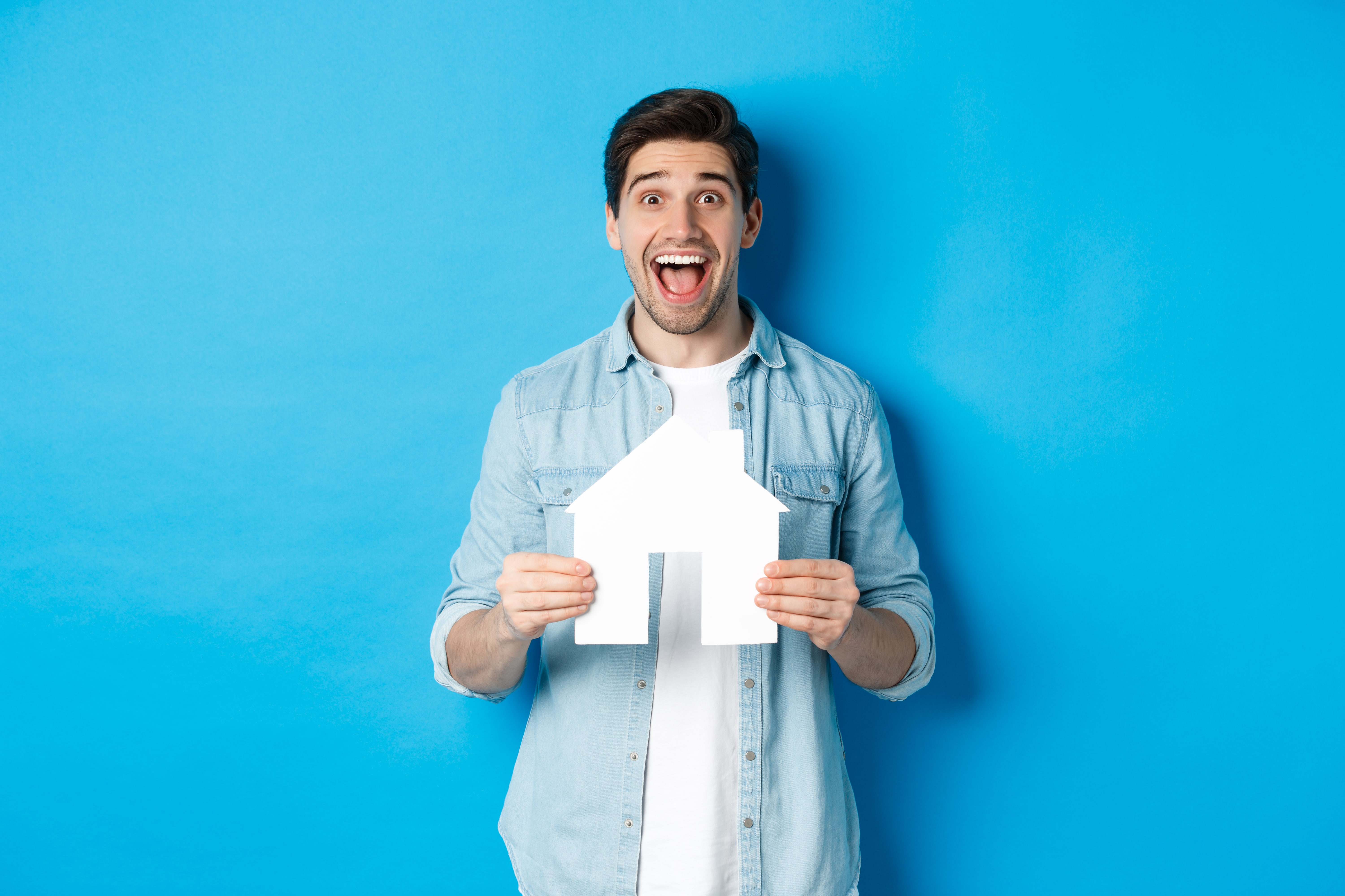 Insurance Mortgage Real Estate Concept Happy Man Holding House Model Smiling Excited Buying Property Renting Apartment Standing Against Blue Background Min
