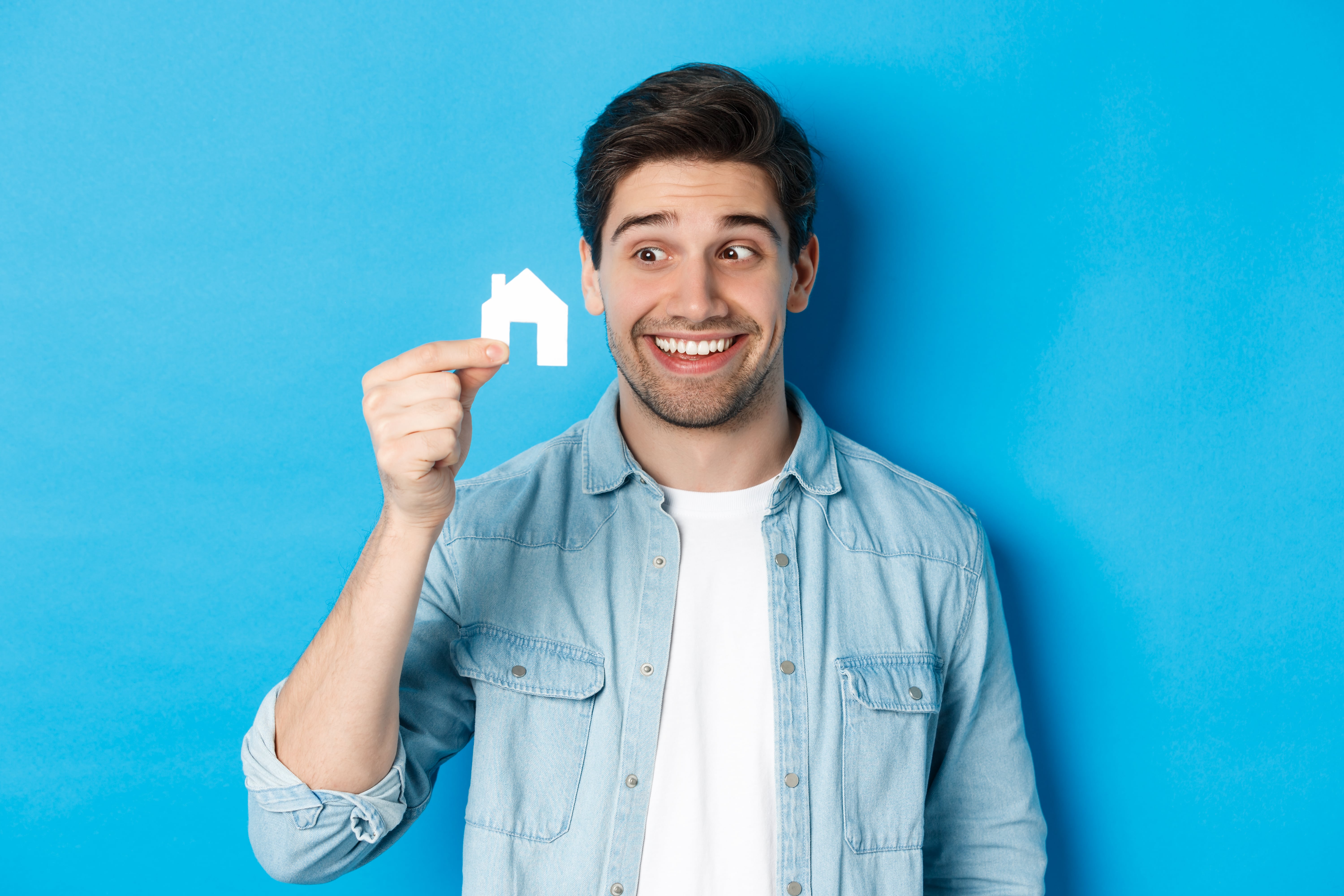 Real Estate Concept Excited Guy Looking Small House Model Smiling Renting Apartment Standing Blue Background Min